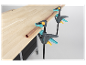 Des serre-joints Wolcraft maintiennent un tube de cuivre sur une table en bois.