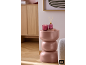 Bougie allumée et diffuseur de parfum sur une table d'appoint rose dans un salon moderne.