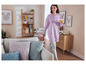 Une femme portant un sweat-shirt rose Mickey Mouse marche dans un salon avec des coussins.