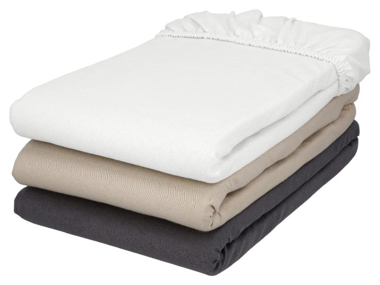 Pile de draps-housses en blanc, beige et gris