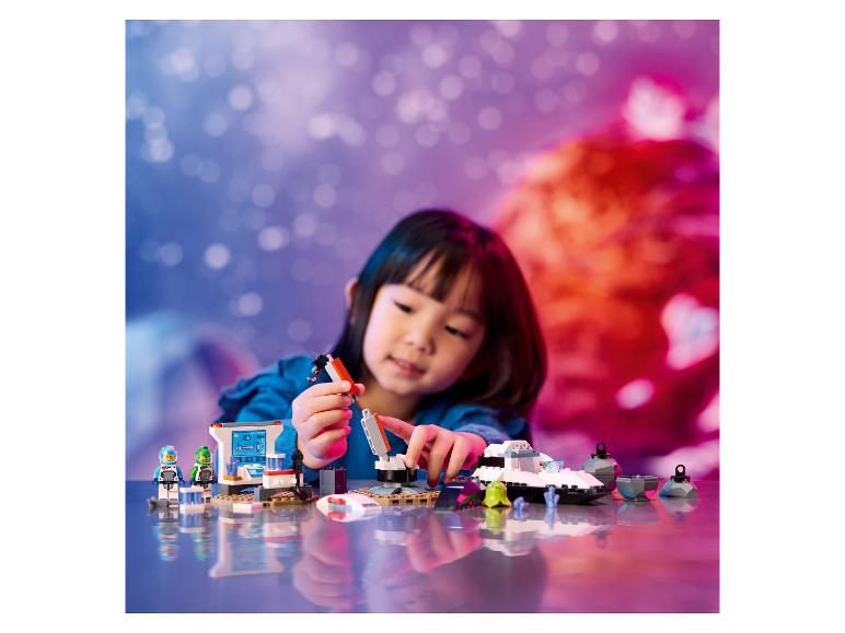 Une enfant joue avec des LEGO City : Space, comprenant un vaisseau spatial et une base spatiale.