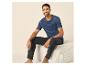 Homme souriant assis, vêtu d'un t-shirt bleu foncé et d'un pantalon noir.