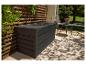 Coffre de rangement de jardin gris foncé sur une terrasse avec treillis en bois et mobilier de jardin.