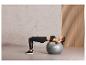 Une femme fait des exercices abdominaux sur un ballon de fitness gris de Crivit.