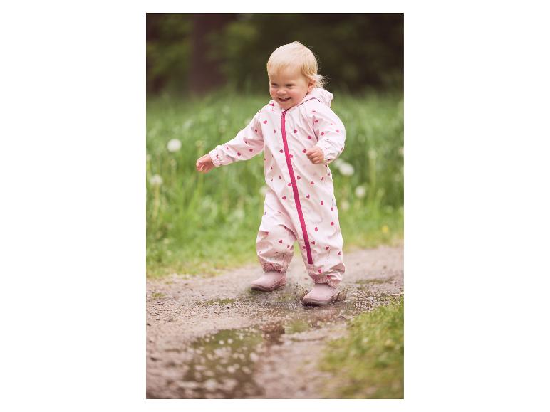 Bébé en combinaison de pluie rose LUPILU® pataugeant dans une flaque