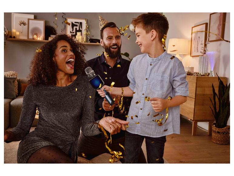 Une femme chante dans un micro de karaoké lors d'une fête avec sa famille.