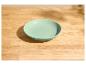 Bol vert menthe sur une table en bois clair avec des ombres