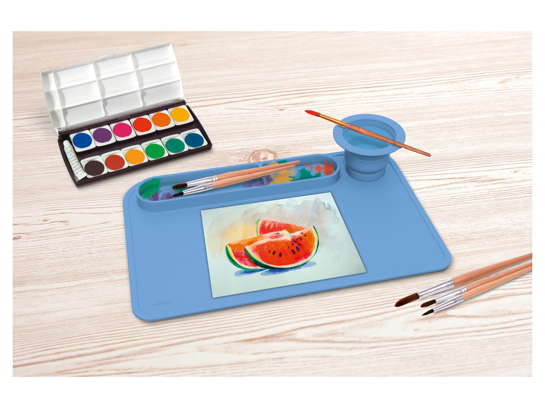 Un set d'aquarelles, des pinceaux et un tapis en silicone bleu pour peindre.