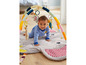 Un bébé sur un tapis de jeu avec un arc avec des jouets, y compris une girafe et un éléphant.