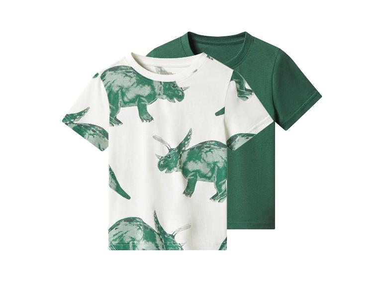 Deux t-shirts pour enfants : un blanc à motifs dinosaures verts, un autre vert uni.