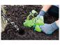 Gants de jardinage et une tarière pour planter une jeune plante dans le jardin.
