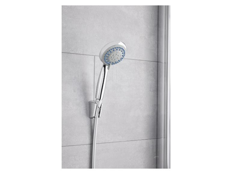 Pomme de douche et flexible chromés fixés au mur d'une salle de bain.