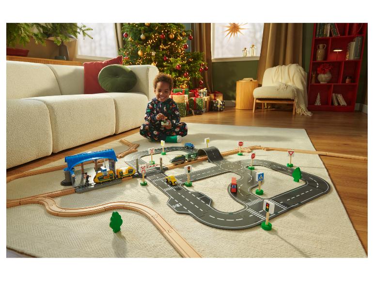 Un enfant joue avec le circuit de train en bois LUPILU® et le train télécommandé.