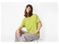 Femme en t-shirt vert lime et jean gris, assise sur un tabouret.