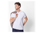 Homme souriant portant un t-shirt blanc et une veste marron sur l'épaule.