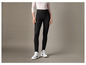 Une femme porte un jean skinny noir et des baskets blanches.