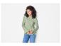 Une femme porte un pull vert clair à manches bouffantes et un jean bleu.