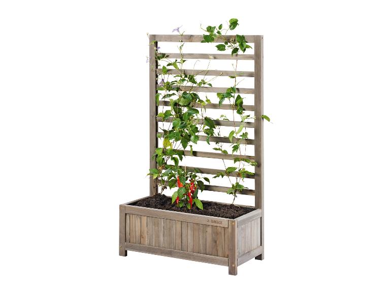 Une jardinière en bois avec un treillis, remplie de plantes et de poivrons.