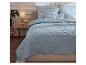 Couette matelassée bleu clair et linge de lit fleuri.