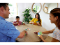 Famille jouant à un jeu de cartes autour d'une table en bois, souriante et engagée.