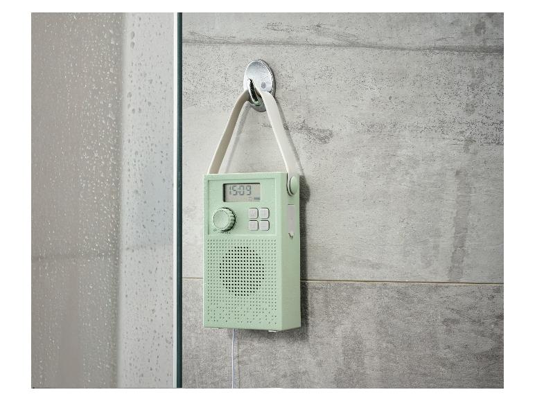 Radio de douche vert menthe avec affichage numérique accrochée à un mur carrelé.