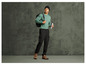 Homme avec un pull vert, un pantalon noir, un sac à dos et une bouteille d'eau.