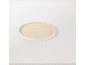 Assiette plate beige et blanche sur une nappe blanche.
