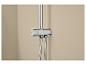 Mitigeur de douche chromé avec thermostat et deux flexibles sur un mur beige.