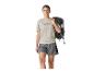 Femme en t-shirt beige imprimé montagne et short gris, avec un sac à dos noir sur l'épaule.