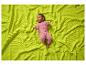 Bébé en grenouillère rose allongé sur une couverture gaufrée vert lime