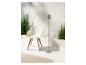 Chaise design, lampe sur pied et plantes vertes dans un décor minimaliste.