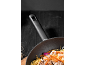 Wok avec nouilles, viande et légumes sur fond sombre.
