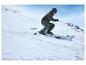 Un skieur en veste verte et casque descend une pente.