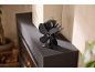 Ventilateur de poêle noir alimenté par la chaleur sur une cheminée moderne, améliorant la distribution de la chaleur.