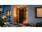 Porte d'entrée décorée d'une guirlande de Noël lumineuse, de neige et d'une lanterne.