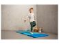 Un garçon sautant sur un tapis de gymnastique bleu.