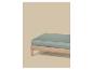 Drap-housse vert clair sur un cadre de lit en bois sur fond beige.