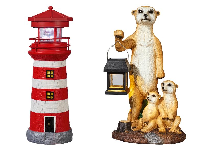 Phare rayé rouge et blanc et famille de suricates tenant une lanterne, tous deux décorations de jardin solaires.