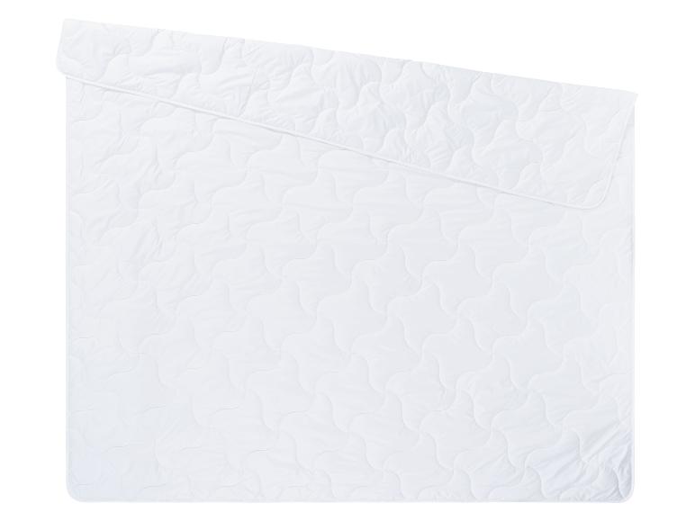Couette et protège-matelas blancs matelassés.