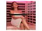 Femme en serviette se relaxant dans un sauna avec luminothérapie rouge