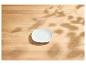 Soucoupe blanche sur une table en bois clair avec des ombres de feuilles.
