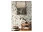 Mur avec papier peint floral, tableau abstrait, banc, coussins et couverture.