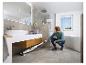 Homme nettoyant le sol d'une salle de bain moderne avec un nettoyeur vapeur.