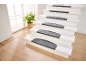 Escalier blanc avec tapis antidérapants gris, plante en pot et parquet clair.