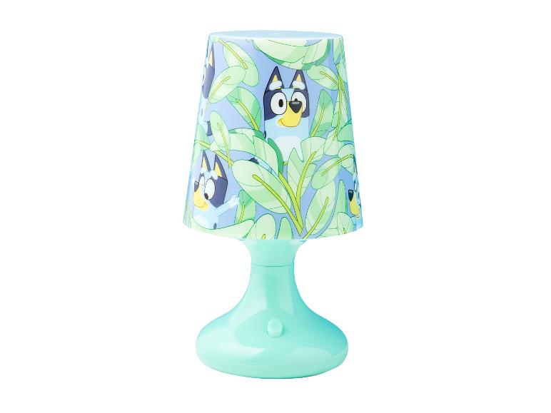 Lampe de table thème Bluey avec une base bleu clair et un abat-jour représentant Bluey et Bingo parmi des feuilles vertes.
