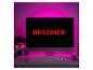 Un moniteur avec le texte rouge 'BRILONER', un clavier et une souris sur un bureau éclairé en rose.