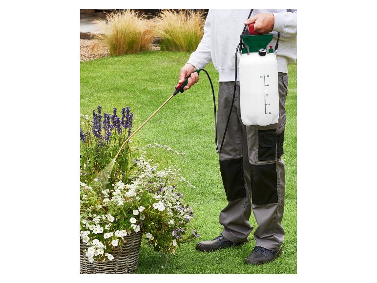 Personne pulvérisant des plantes dans un jardin avec un pulvérisateur à pression dorsal.