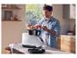 Homme ajoutant des légumes coupés à un robot de cuisine.