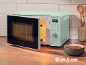 Four à micro-ondes vert menthe avec porte ouverte, affichant une horloge numérique et des commandes, à côté d'un bol de soupe.
