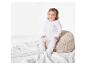 Un bébé assis sur un coussin en peluche, porte un pyjama blanc avec un motif nuage.